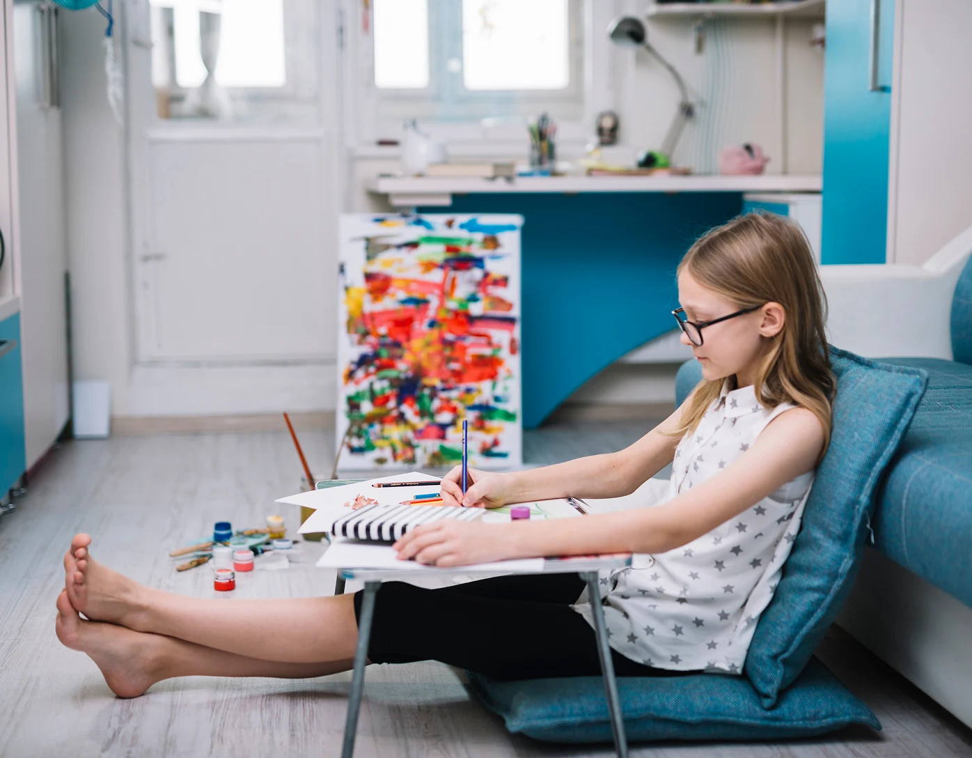 Child studying and drawing at a low table in a bright home study space